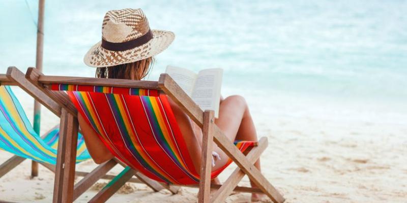 Mujer leyendo un libro en la playa / Pixabay