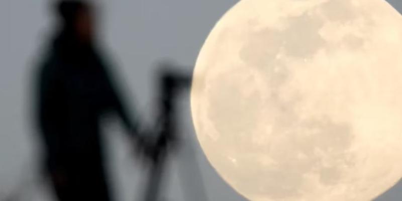 Luna y señor mirando con un telescopio