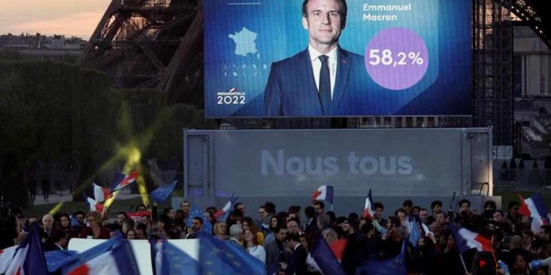Una pantalla colocada en la Torre Eiffel proyecta una imagen de Macron y su resultado 