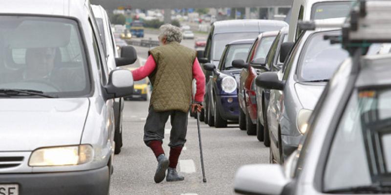 Un hombre transita entre los coches pidiendo limosna. 