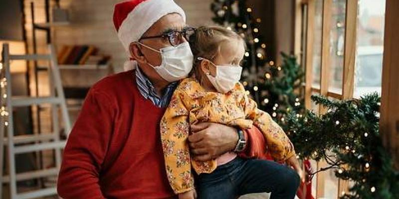 Mascarillas de Navidad Abuelo con su nieta en una reunión familiar mirando por la ventana / Foto: iStock