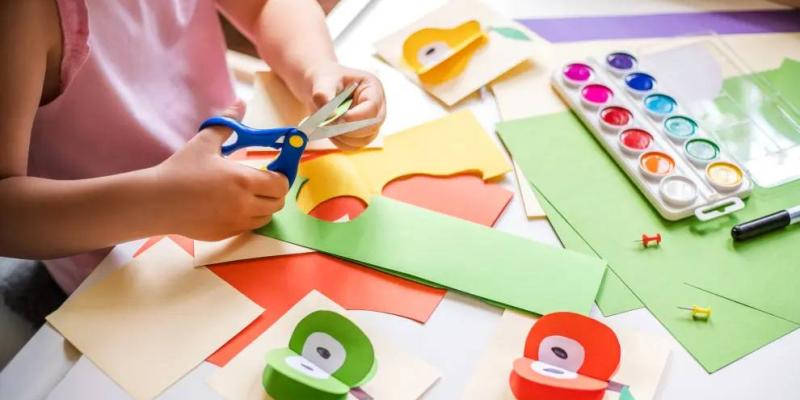 Niña recortando cartulinas con su material escolar