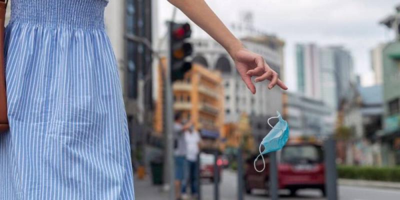 Una joven tira la mascarilla al suelo / GETTY Una joven tira la mascarilla al suelo, ¿dónde tendremos que seguir llevándola?