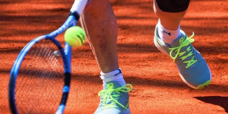 Un tenista golpea una pelota en una pista de tenis