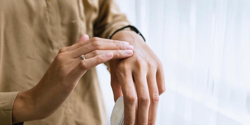 Manos de una mujer aplicándose crema