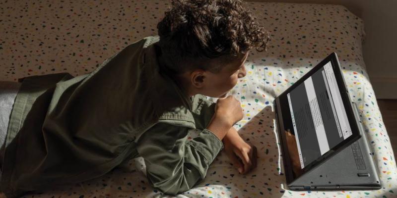 Un joven sigue las clases a través de un ordenador tumbado en una cama / Tecnobility