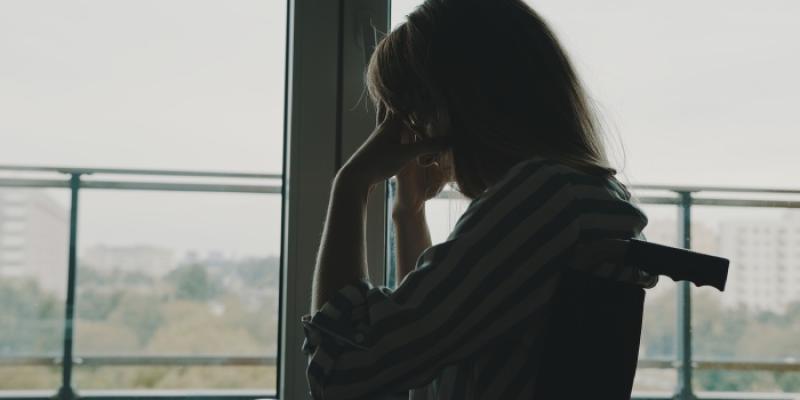 Una mujer en silla de ruedas está cabizbaja y triste 