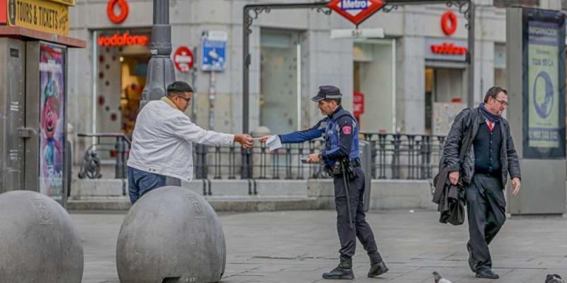 Las comunidades imponen más multas y mucho más duras para las personas que se salten el confinamiento Un policía municipal de Madrid pone una multa a un viandante por no respetar la cuarentena en Madrid. E.P.