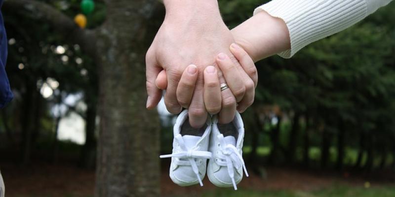Nacimientos en España / Pixabay Manos de dos padres sujetando unos patucos