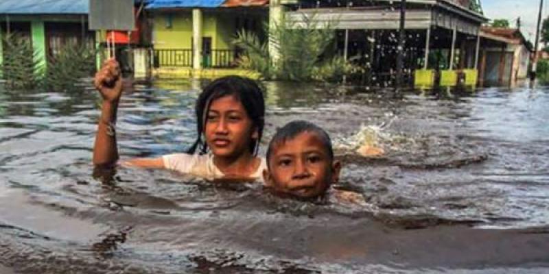 Unos niños caminan entre las aguas de las inundaciones en Palangka Raya, en Kalimantan Central (Indonesia).