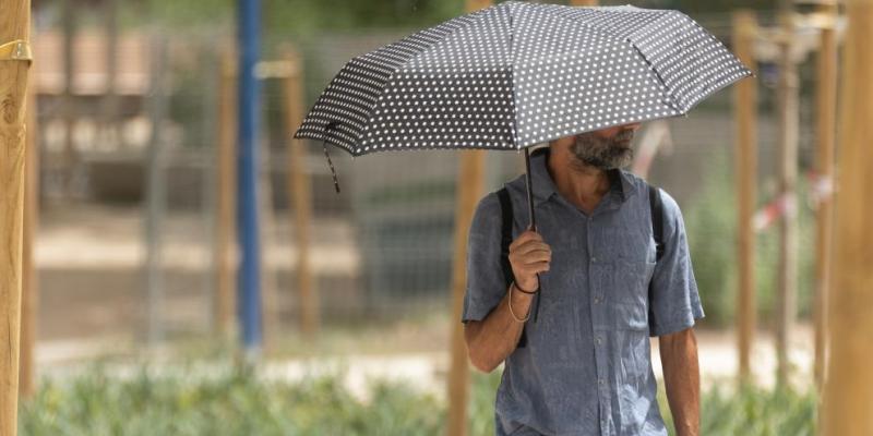 Imagen de un hombre con paraguas por la calle para protegerse del sol/20Minutos ¿Cuándo llega la segunda ola de calor a España?