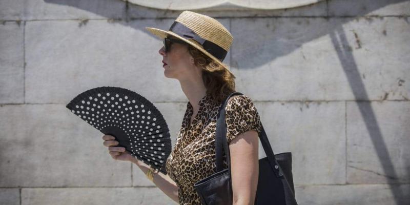 Imagen de una mujer por la calle con abanico/Público La ola de calor alcanza hasta los 44 grados