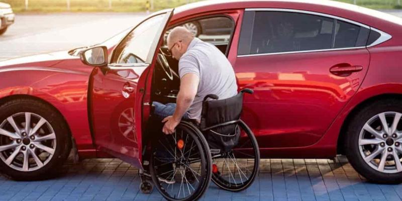 Imagen de una persona en silla de ruedas y su coche/Tododisca Las personas con discapacidad cuentan con beneficios a la hora de comprar un coche