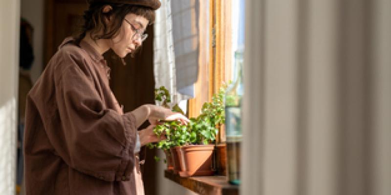 Imagen de una chica con una planta/envatoelements Beneficios de tener plantas alrededor de nuestro hogar