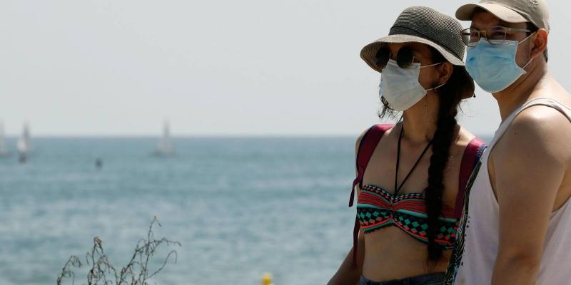 Personas llevando la mascarilla en la playa