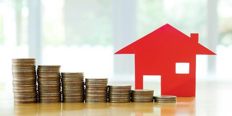 El precio de la vivienda ha subido en este primer trimestre de 2022/ Inmobling Montañas de monedas al lado de la estructura de una casa pequeña