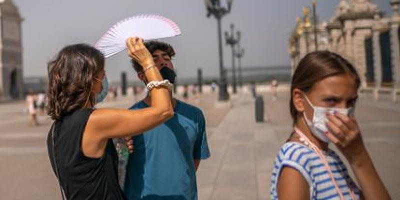 Una mujer protege a un chico del calor con un abanico