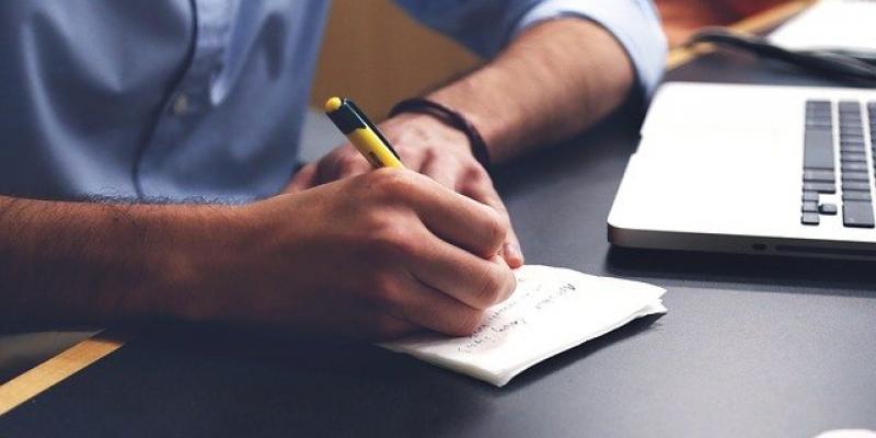 Aumenta la productividad en las empresas gracias al teletrabajo Manos de un señor teletrabajando con su portátil y un bloc de notas / Pixabay