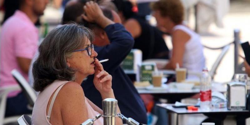 Prohibir fumar en las terrazas Mujer fumando en la terraza de un bar