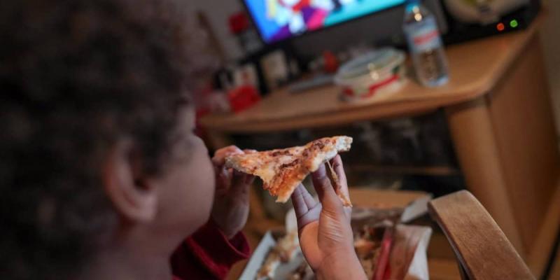 Imagen de un niño comiendo pizza/Europa Press Los consumidores reclaman una ley estricta contra la publicidad de alimentos