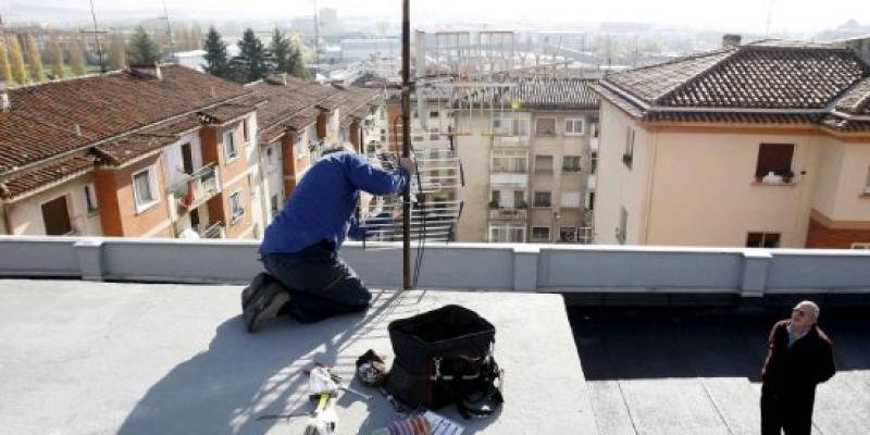 Un señor observa las labores de trabajo de un antenista en una azotea. Un señor observa las labores de trabajo de un antenista en una azotea.