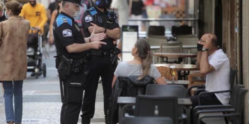 Entran en vigor las restricciones y recomendaciones para frenar los rebrotes. Foto: EFE. Agentes explicandos las restricciones y recomendaciones para frenar el virus en A Coruña.
