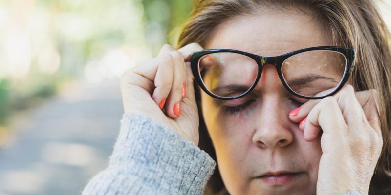 Una mujer levanta sus gafas con una mano y con la otra se toca un ojo