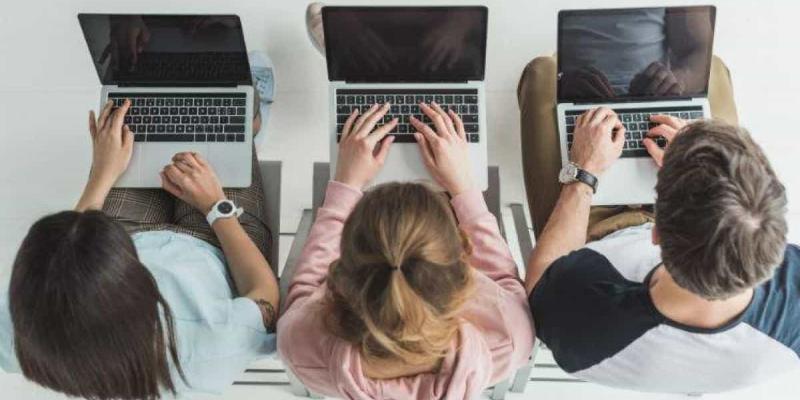 Imagen de tres estudiantes con ordenadores/La Vanguardia Las universidades optan por la digitalización