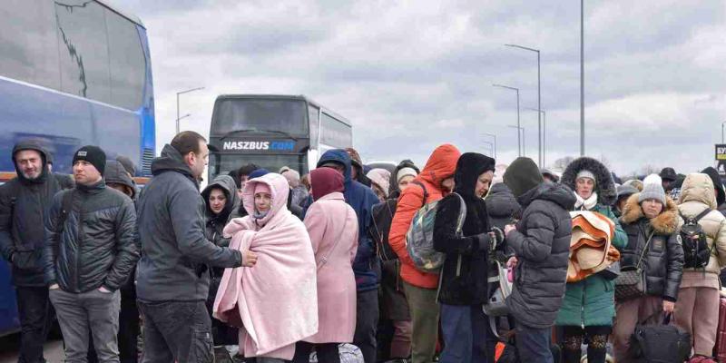 Multitud de refugiados se amontona a la entrada de un autobús