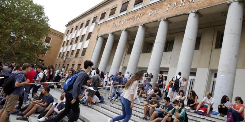 Jóvenes sentado en la escalinata de una facultad universitaria 