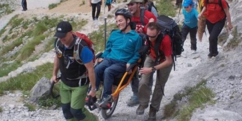 Persona con discapacidad haciendo turismo en la montaña con un equipo de apoyo