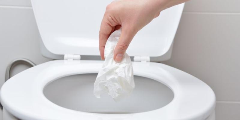 Imagen de una persona tirando un papel en el váter/El HuffPost Objetos que no se pueden tirar al váter