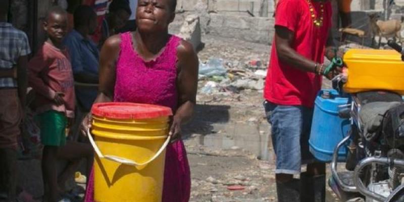 Una mujer de Puerto Príncipe (Haití) transporta agua que ha comprado a un comerciante local.