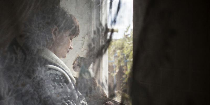 Una mujer que sufre violencia mira por la ventana abrazando a su gato