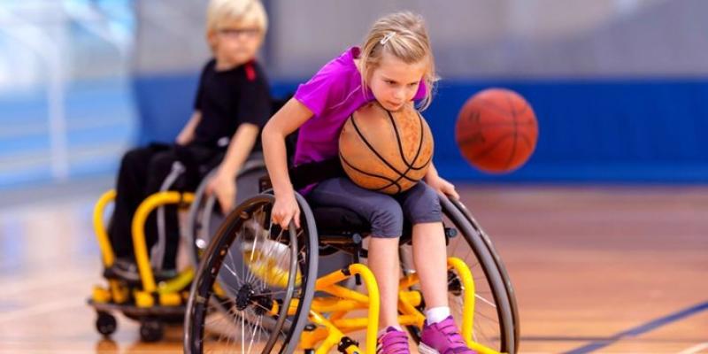 Niña en silla de ruedas jugando al baloncesto