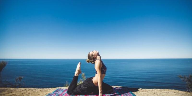 Chica haciendo yoga con el mar de fondo