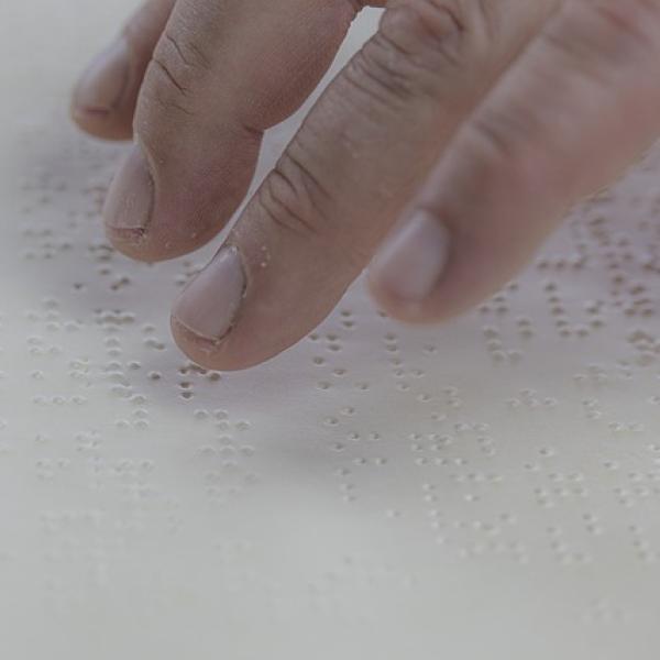 Dedos de una persona leyendo en braille