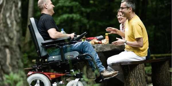 Una persona con discapacidad física habla con otra persona en un parque 