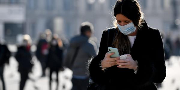 Mujer mirando un mensaje con mascarilla