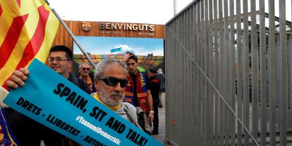 Un hombre sostiene una pancarta de "Tsunami Democràtic" en los aledaños del Camp Nou antes del partido aplazado de LaLiga que disputan este miércoles Barcelona y Real Madrid./Foto: Toni Albir/EFE