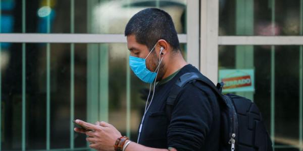 Coronavirus | Un hombre con mascarilla consulta su teléfono / Getty