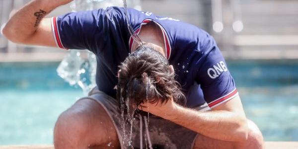 Un joven se tira una botella de agua por encima para combatir una ola de calor en Madrid. 