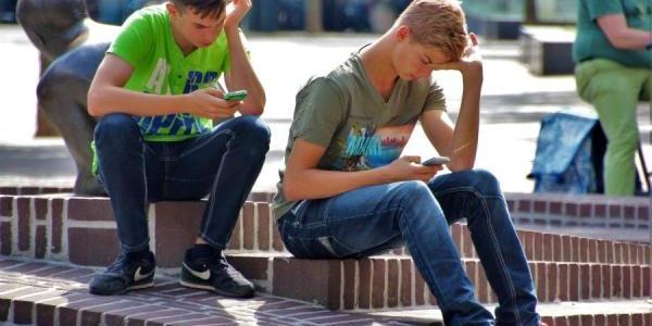 Dos adolescentes consultan sus móviles sentados en una escalera