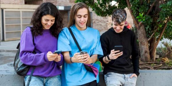Varios adolescentes consultan sus móviles 