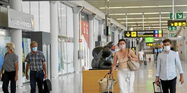 Turistas transitan por el aeropuerto de Menorca con mascarilla 