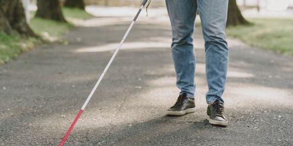Joven con discapacidad visual pasea por un parque 