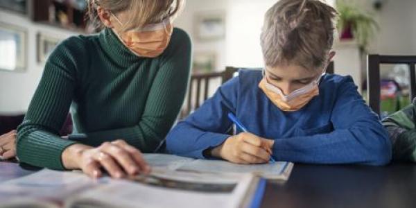 Bajas médicas: una madre con su hijo estudiando en casa