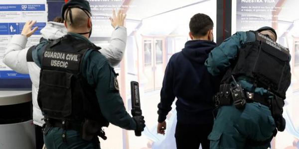 Dos guardias civiles cachean a dos jóvenes en la estación de metro de Arganda del Rey.