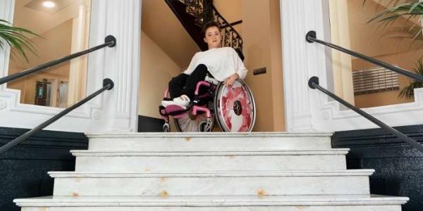 Persona en silla de ruedas en un portal poco accesible