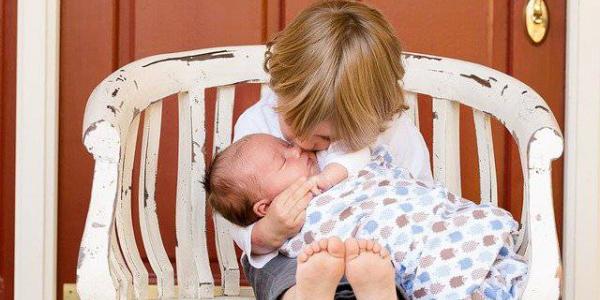 Dos bebés, hermanos, dándose un besito